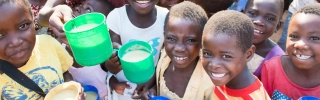 Smiling group of children with mugs of porridge