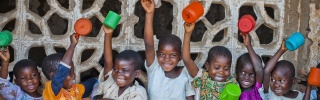 Group of children raising mugs in the air