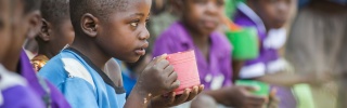 Child eating from mug looking into the distance