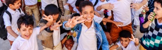 Happy, smiling children wave at camera in school