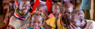 Children in a classroom sitting a table and laughing with each other