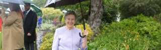 Mary's Meals supporter standing in garden under umbrella