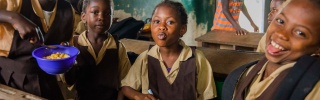 Children smiling and eating food in classroom in Liberia