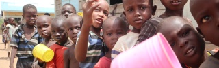 children in Kenya queuing for their lunch, mugs in hand