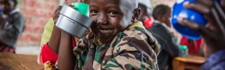 A smiling child poses with a mug in a classroom in Kenya