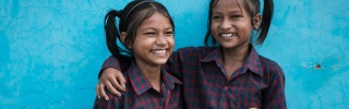 Siblings Jainab and Jubaida stand together smiling