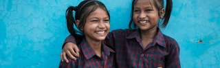 Siblings Jainab and Jubaida stand together smiling