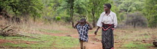 Mother and young son walk through bush in rural Zambia together