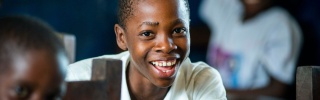 A boy sits in a classroom, smiling