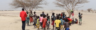 Robert a teacher in Kenya with his class standing outside near two trees