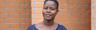 A young woman, Bernadette, stands outside the school she teaches at