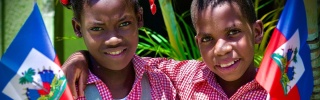 Two smiling children holding the Haiti flag