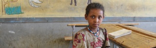A girl sits at a classroom desk in Ethiopia.