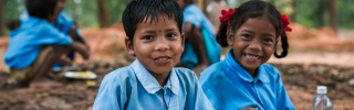Two children sit together eating Mary's Meals