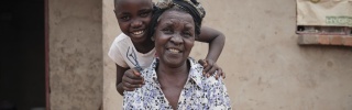 A grandmother, Elly, sits, while her granddaughter, Grace, stands behind her