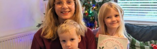 Victoria and her children in a living room, a boy holds a Mary's Meals mug and a girl holds a Santa plate