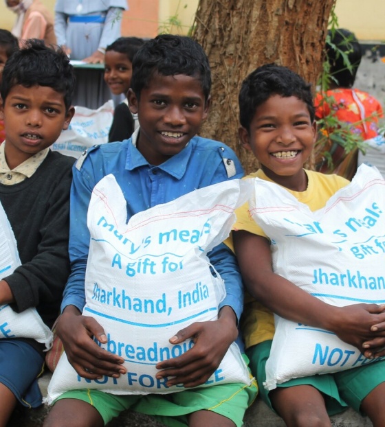 Children in India holding bags of take home rations 