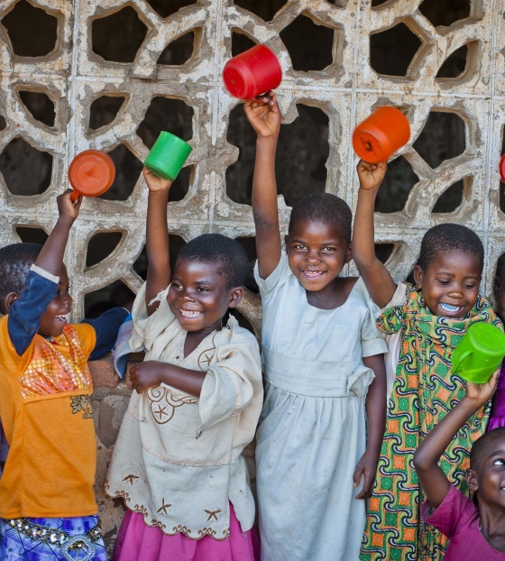 Group of children raising mugs in the air