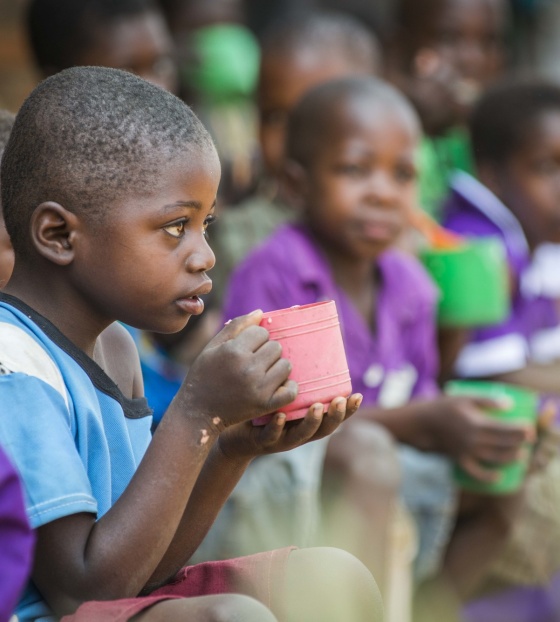 Child eating from mug looking into the distance
