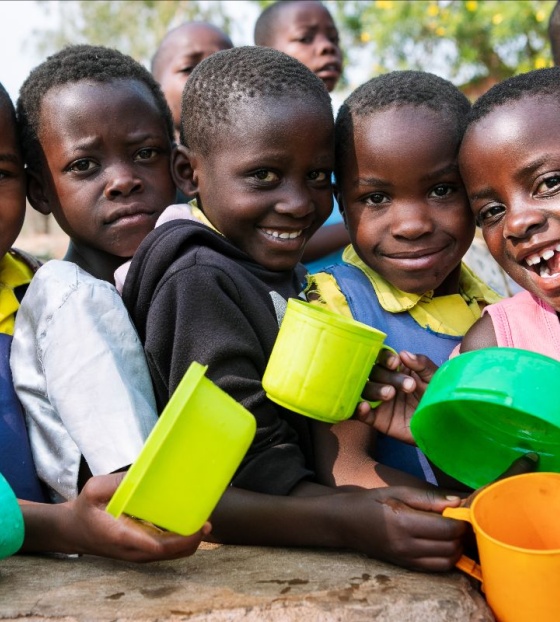 Group of girls holding colourful mugs smiling to camera