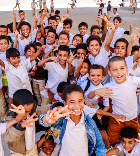 Happy, smiling children wave at camera in school