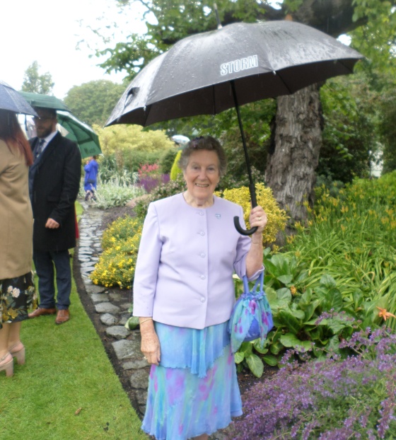 Mary's Meals supporter standing in garden under umbrella