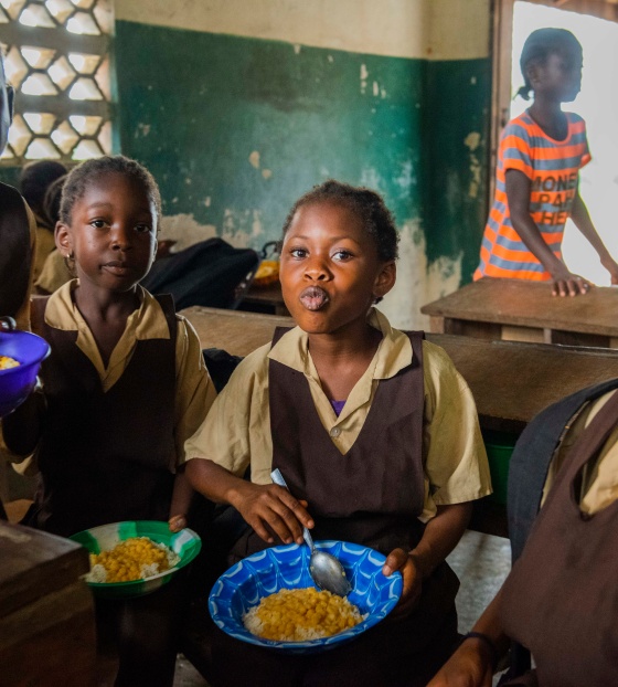 Children smiling and eating food in classroom in Liberia