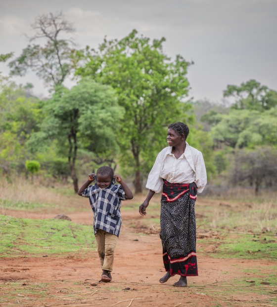 Mother and young son walk through bush in rural Zambia together