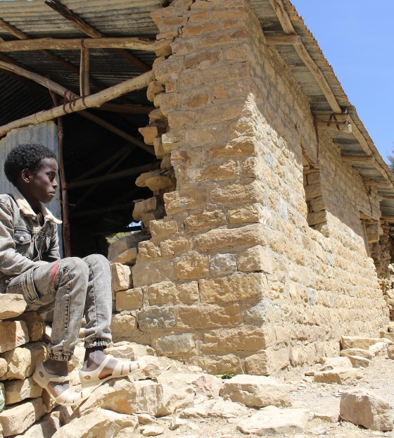 Child in Ethiopia sitting outside destroyed school building