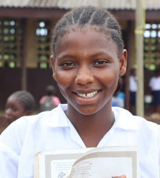Isatu, a girl from Liberia, smiling outside her school