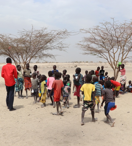 Robert a teacher in Kenya with his class standing outside near two trees