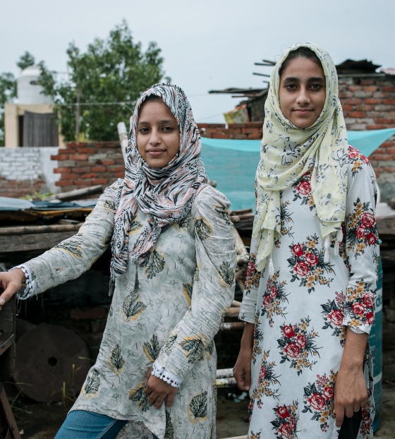 Two young sisters, Fatima and Soni, stand outside in India