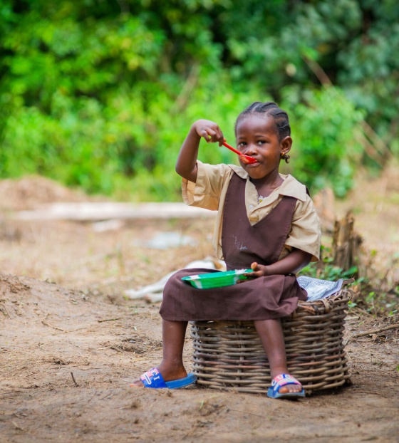 A girl sitting outside eating Mary's Meals in Liberia
