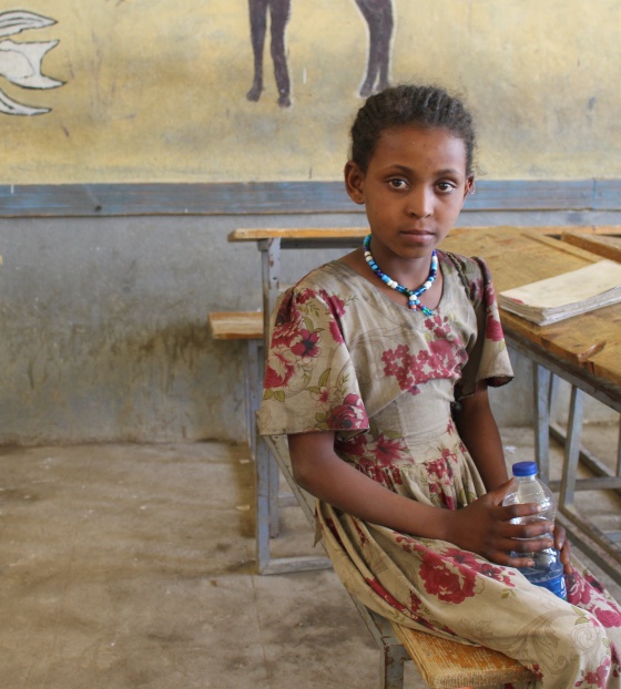 A girl sits at a classroom desk in Ethiopia.