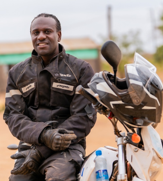 Amos Lungu, a school feeding officer from Zambia, sits on a motorbike