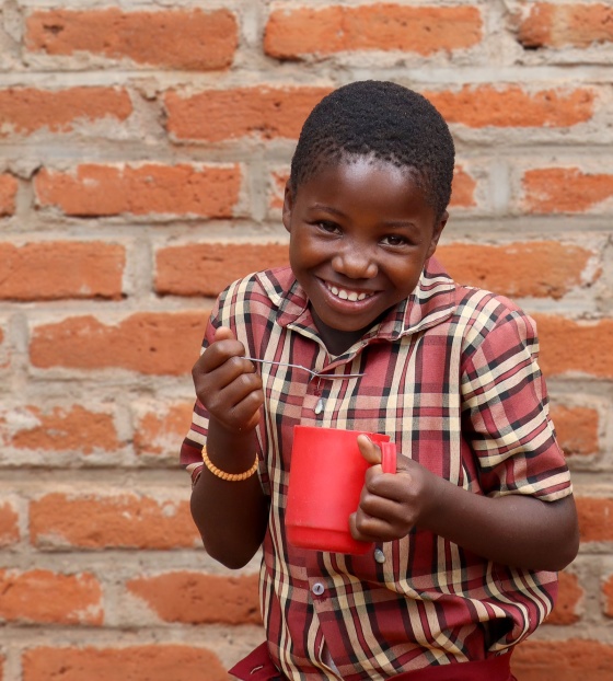 Image of a happy child holding their school meal
