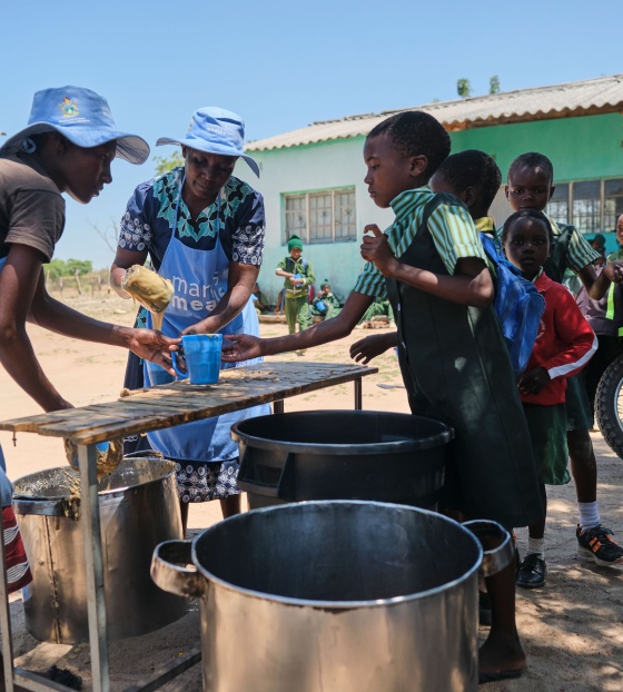 Image of school meals being handed to children by volunteers in Zimbabwe