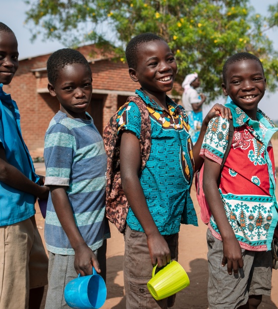 Four boys outside in Malawi standing with mugs