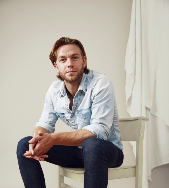 Actor Wilf Scolding sitting on a chair