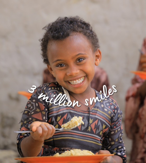 child smiling to camera with red plate and spoon with food - text overlay with 3 million smiles