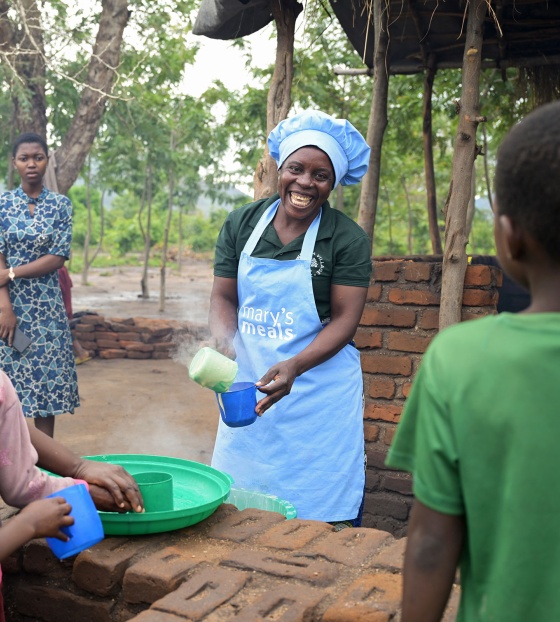 Image of a volunteer cook serving school meals