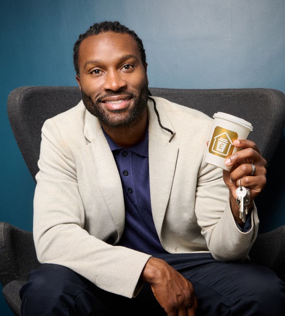 Stuart Douglas sitting on a chair holding a coffee cup and set of keys