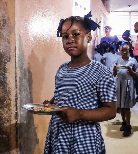 An image of a child in Haiti holding their school meal