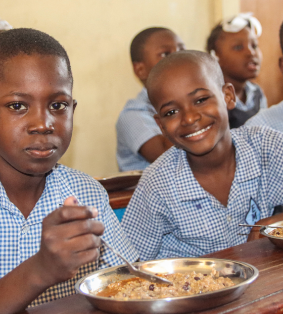 Three boys eating Mary's Meals at school in Haiti