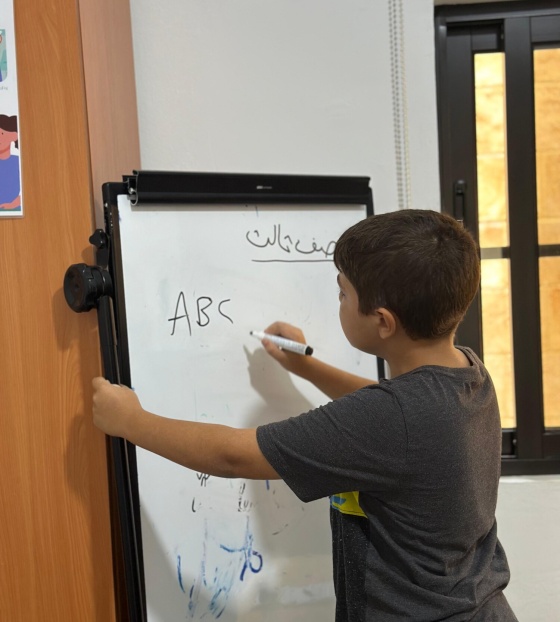 A young boy writes on a white board