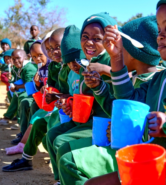 Children eating from mugs outside
