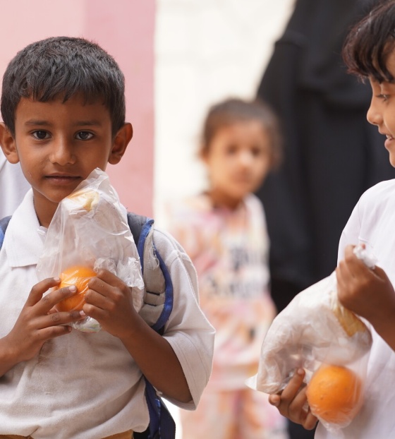 Children holding oranges outside