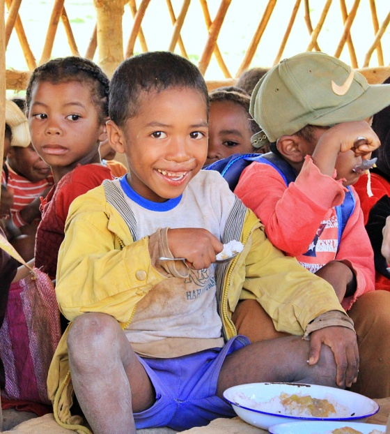 A child eats food from a bowl while smiling