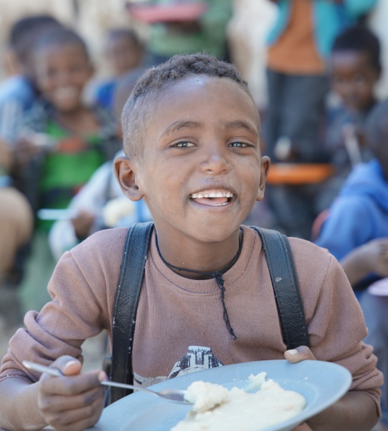 A happy boy eating a bowl of food