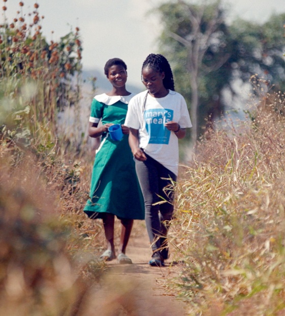 Image of Lettie walking with a school child on her way to school